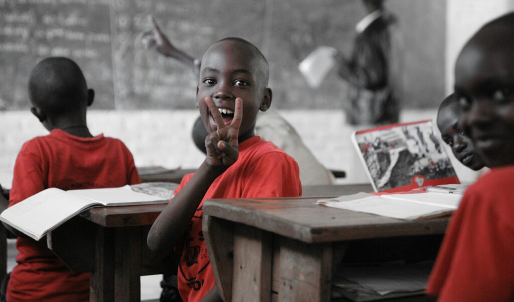 A young boy in a classroom turn away from the blackboard smiling