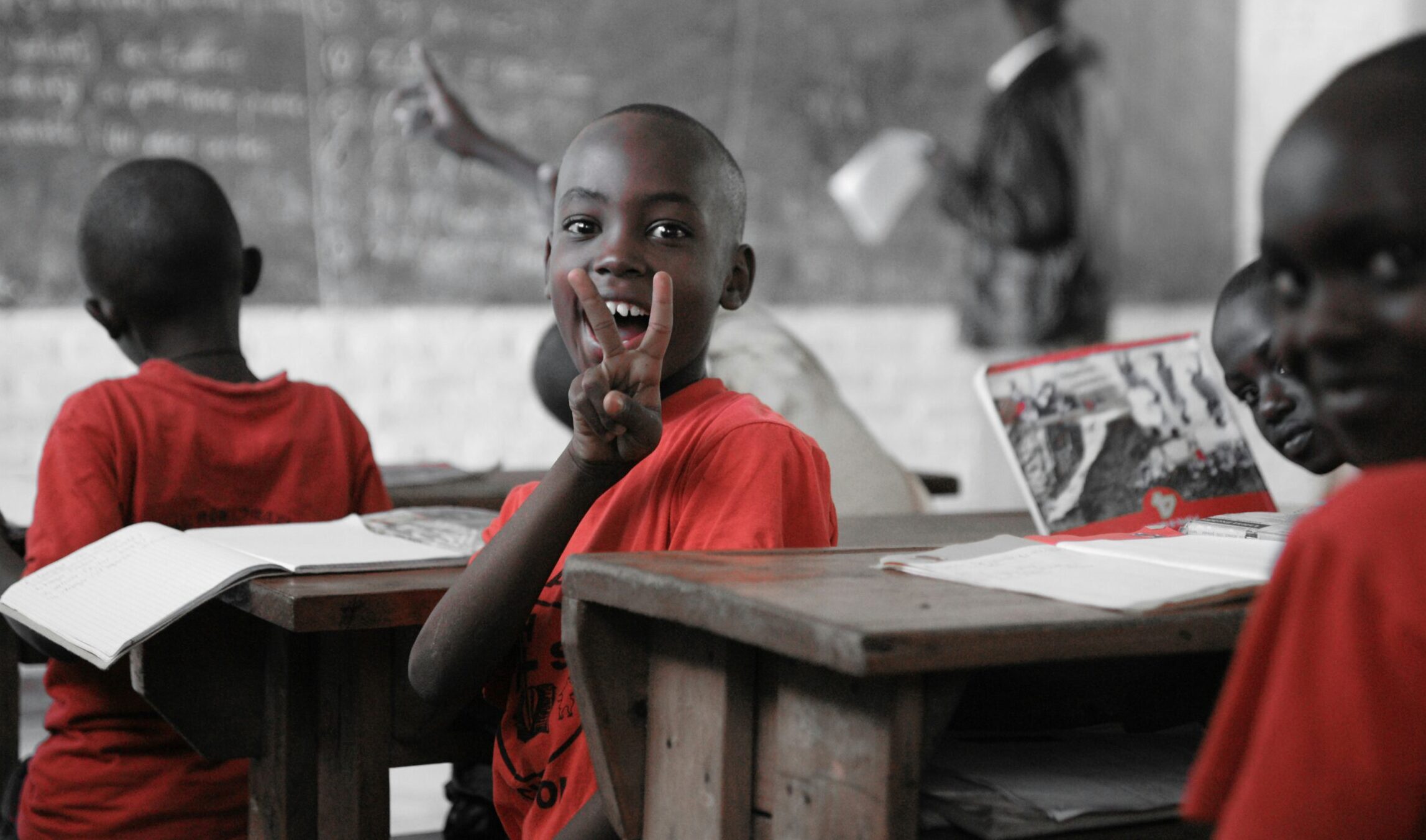 A young boy in a classroom turn away from the blackboard smiling