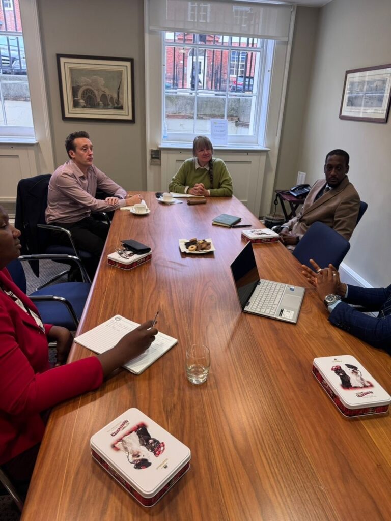 six people sitting at a desk with papers infront of them in discussion during a IBLF visit with support from ROLE UK programme